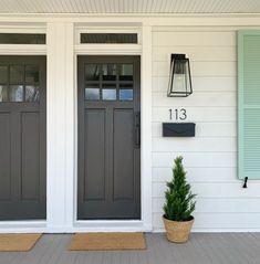 the front door of a house with two potted plants on the porch and number 13