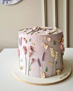 a pink cake with flowers on it sitting on top of a white table next to a clock