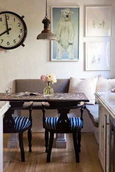 a table with two chairs and a clock on the wall above it in a living room