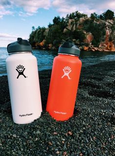 two hydro flasks are sitting on the beach