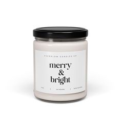 a white candle with black lid and merry and bright label on the front, sitting against a white background