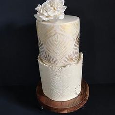 a three tiered cake with white flowers on the top and bottom, sitting on a wooden stand