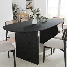 a dining room table with four chairs and a vase on the table in front of it