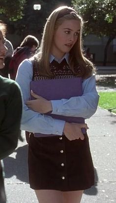 two young women standing next to each other in the street, one holding a binder