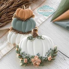 two decorated pumpkins sitting on top of a table next to a basket filled with hay