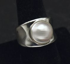 Beautiful vintage sterling silver ring, bezel set with a lovely and large akoya pearl. A smart, sleek, modern design. The pearl is approximately 1/2 inch in diameter. Size 9 1/4 11.4g Marked "925 WW HONG KONG" Classic Silver Cabochon Pearl Ring, Formal Silver Pearl Ring With Polished Finish, Modern Oval Pearl Ring For Anniversary, Classic Silver Pearl Ring For Formal Occasions, Minimalist Silver Pearl Ring With Polished Finish, Classic Silver Pearl Ring With Polished Finish, Classic White Pearl Ring With Bezel Setting, Modern Silver Pearl Ring With Polished Finish, White Pearl Ring With Bezel Setting In Classic Style