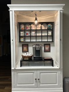 a coffee maker is sitting on top of a white cabinet with glass shelves above it