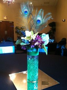 a vase filled with flowers and feathers on top of a table