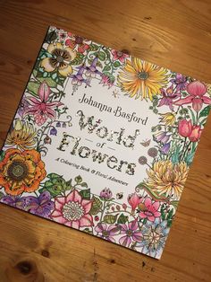 a book with flowers on it sitting on top of a wooden table in front of a wood floor