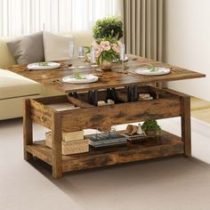 a wooden table with plates and bowls on it in front of a couch, coffee table