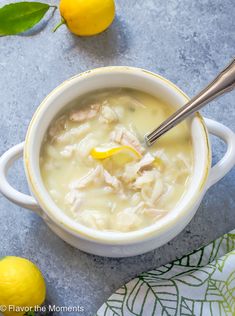 a bowl of chicken and dumpling soup with a spoon in it next to some lemons