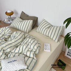 there is a bed with many pillows on it and a plant next to the bed