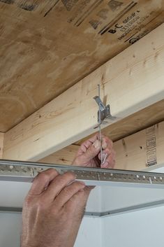 a man is working on the underside of a wooden structure with nails and pliers