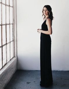 a woman standing in front of a window with her hand on her hip and looking off to the side