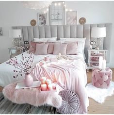 a bedroom decorated in pink and white with candles on the nightstands, bedding and decor