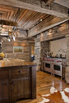 an old log cabin kitchen with wood flooring and wooden beams on the ceiling, along with stainless steel appliances