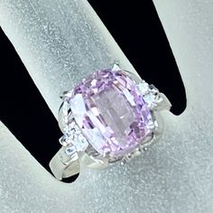 a ring with an oval shaped pink stone surrounded by diamonds