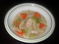 a white bowl filled with chicken noodle soup on top of a black countertop