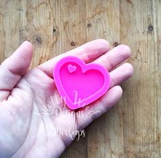 a hand holding a pink heart shaped object