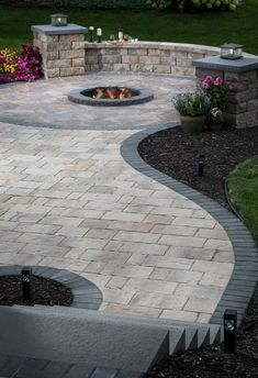 an outdoor fire pit surrounded by landscaping