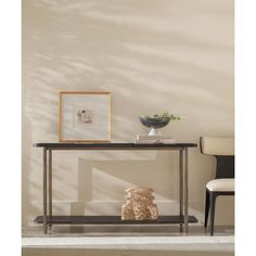 a table with a vase on it next to a chair and a framed photograph in the corner