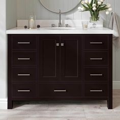 a bathroom vanity with a mirror above it and flowers in the vase on the counter