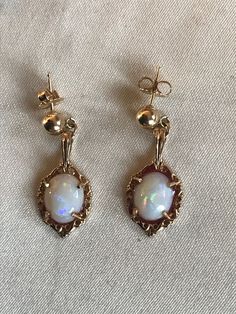 This is a very pretty pair of white Australian opal pendant earrings fashioned in 14 karat gold. The natural opals have a subtle but colorful display of fire that dances around when held in certain light. The photos were taken in natural daylight in order to present the flashes of color. The framework that the opals are placed in are very pretty and Victorian or Georgian revival style. The pendants are suspended from little round ball post earrings and are meant for pierced ears. The earrings me Georgian Revival, Australian Opal Pendant, Chain Fringe, Gold Fringe, Yellow Gold Chain, Precious Gems, Australian Opal, Opal Pendants, Fringe Earrings