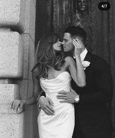 a man and woman kissing in front of a wall