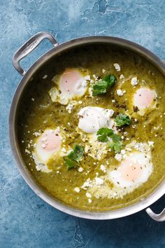 an overhead view of eggs in a green sauce with parsley on top, and some bread crumbs