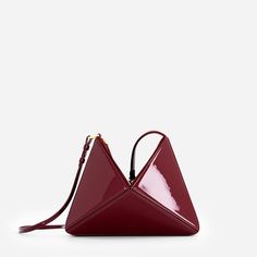 Our architectural, origami inspired shoulder bag, now has a new dimension. It can be converted into a wrist bag just with a quick move. The shoulder strap can easily be removed, so you can slung it from your wrist or use as a clutch. It has plenty of room inside for your essentials including a large phone, small wallet, and 300 ml water bottle. Made from smooth leather and has a suede top with two-way zip fastening. Interior features two slip pockets. Crafted from Italian patent leather. Canvas Contemporary Rectangular Evening Shoulder Bag, Modern Triangle Bag With Removable Pouch, Modern Triangle Shoulder Bag With Removable Pouch, Modern Triangular Shoulder Bag With Removable Pouch, Modern Evening Bag, Triangle Shoulder Bag With Removable Pouch For Travel, Modern Triangle Bag With Detachable Strap, Modern Evening Bag With Removable Pouch, Modern Formal Pouch Shoulder Bag