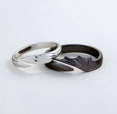 two wedding rings sitting side by side on top of each other, one black and one white