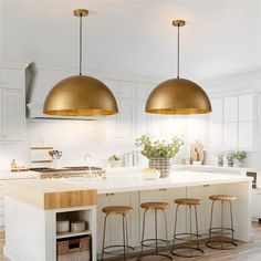 two pendant lights hanging over an island in a kitchen with stools and counter tops