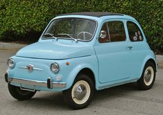 an old blue car is parked in front of some bushes