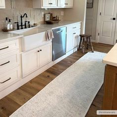 a clean kitchen with white cabinets and wood flooring is seen in this image from the doorway