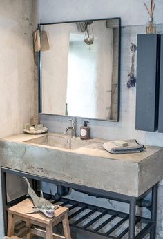 a bathroom sink sitting under a mirror next to a wooden step stool and counter top