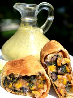 two burritos cut in half on a plate next to a jug of ranch dressing