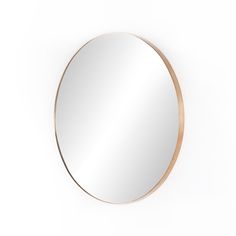 a round mirror on the wall with a gold rim around it and a white background