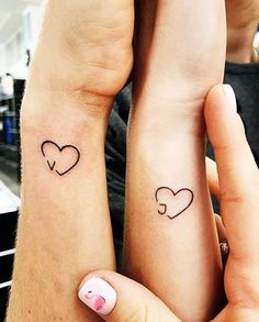 two people with matching tattoos on their arms, one holding the other's hand