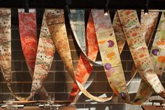 colorful ribbons hanging from the ceiling in front of a brick wall