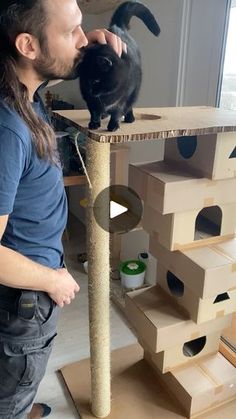 a man standing next to a cat on top of a scratching post