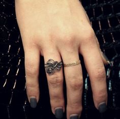 a woman's hand with a tattoo on it and a gold band around her ring