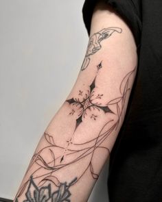 a woman's arm with tattoos on it, and flowers in the middle of her arm