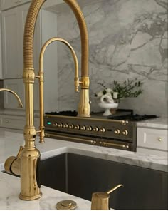 a kitchen with marble counter tops and gold faucets on the sink in front of an oven