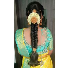 a woman with long hair wearing a yellow sari and holding a flower in her hair