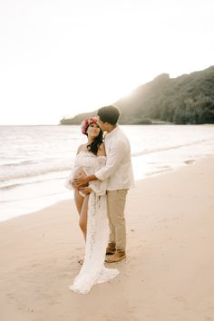 a man and woman standing on top of a sandy beach