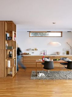 a living room filled with furniture next to a wooden table and book shelf on top of a hard wood floor