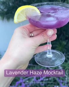 a person holding up a purple drink with lemon wedges in it and the words lavender haze cocktail