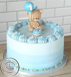 a blue cake with a teddy bear on top