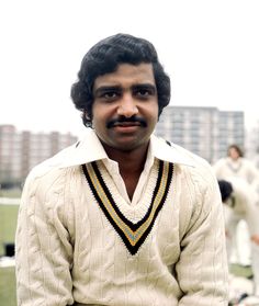 a man in white shirt and black pants standing next to other men wearing white uniforms