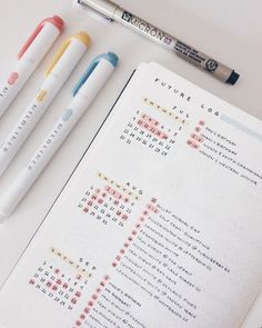 three pens sitting on top of an open notebook